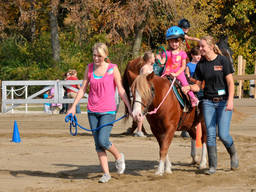 A young horse rider is guided by her horse groom