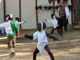 A kid happily showing his fencing skills.