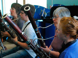 A young boy plays basooon and harmonizes with companions